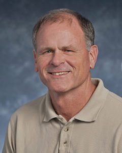Portrait of a man with short light colored hair in a tan polo