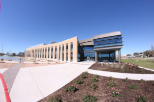 Front view photo of the new and completed TVMDL building with a pond on the left and freshly planted flowers on the right