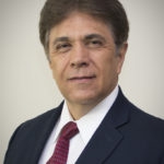 portrait photo of a hispanic man with dark hair in a black suit with a red tie