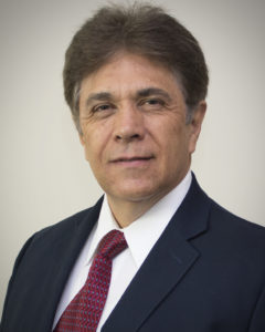 portrait photo of a hispanic man with dark hair in a black suit with a red tie