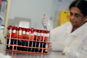 woman with black hair pipetting liquid into tube in laboratory