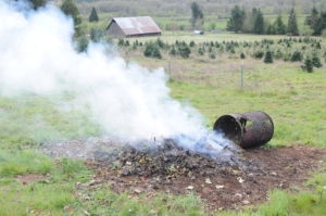 Burning a pile of old wood and composite in a grass field.