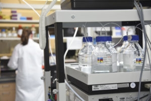 laboratory beakers with a scientist in white coat in the background