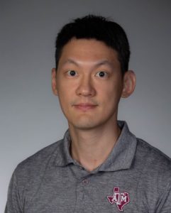 man with black hair and gray shirt posing for a professional portrait