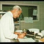 man in white lab coat writing on paper in laboratory