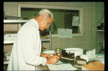 man in white lab coat writing on paper in laboratory