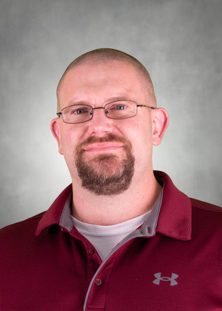 man in red shirt wearing glasses posing for a portrait